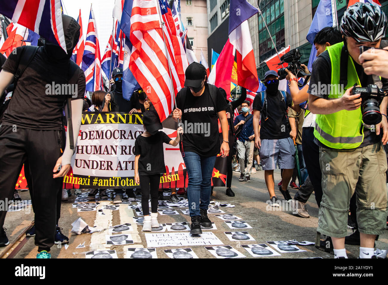 Une femme et sa fille à pied sur des affiches de Xi Jinping's face au cours de la manifestation.Pendant le 17ème week-end de manifestations consécutives, les manifestants ont marché dans le cadre d'une initiative mondiale contre le totalitarisme. Les manifestants scandaient des slogans et continué de solliciter de la cinq exigences à satisfaire. Manifestants ont affronté la police anti-émeute et ont été frappés avec des gaz lacrymogènes, des balles en caoutchouc, et un canon à eau jusqu'à ce que plusieurs ont finalement été arrêtés. Banque D'Images