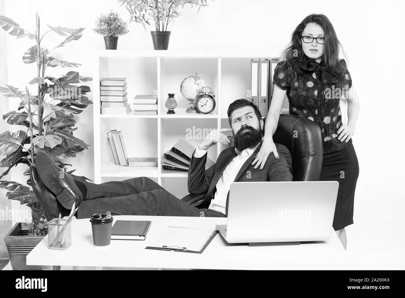 Bureau patron paresseux. Offrir un massage. Hipster barbu homme patron s'asseoir dans un fauteuil en cuir de l'intérieur du bureau. Patron et secrétaire girl au lieu de travail. Relations au travail. Les gens d'affaires et le personnel du concept. Banque D'Images