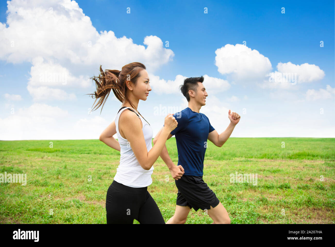 Happy young Couple jogging et exécuté sur l'herbe Banque D'Images