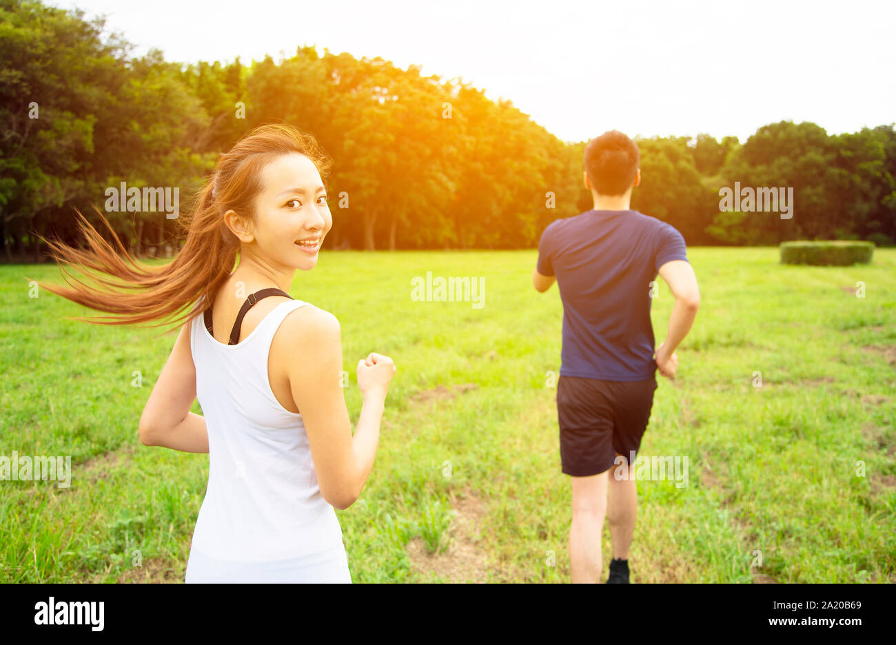 Jeune couple d'exécution sur l'herbe au matin Banque D'Images