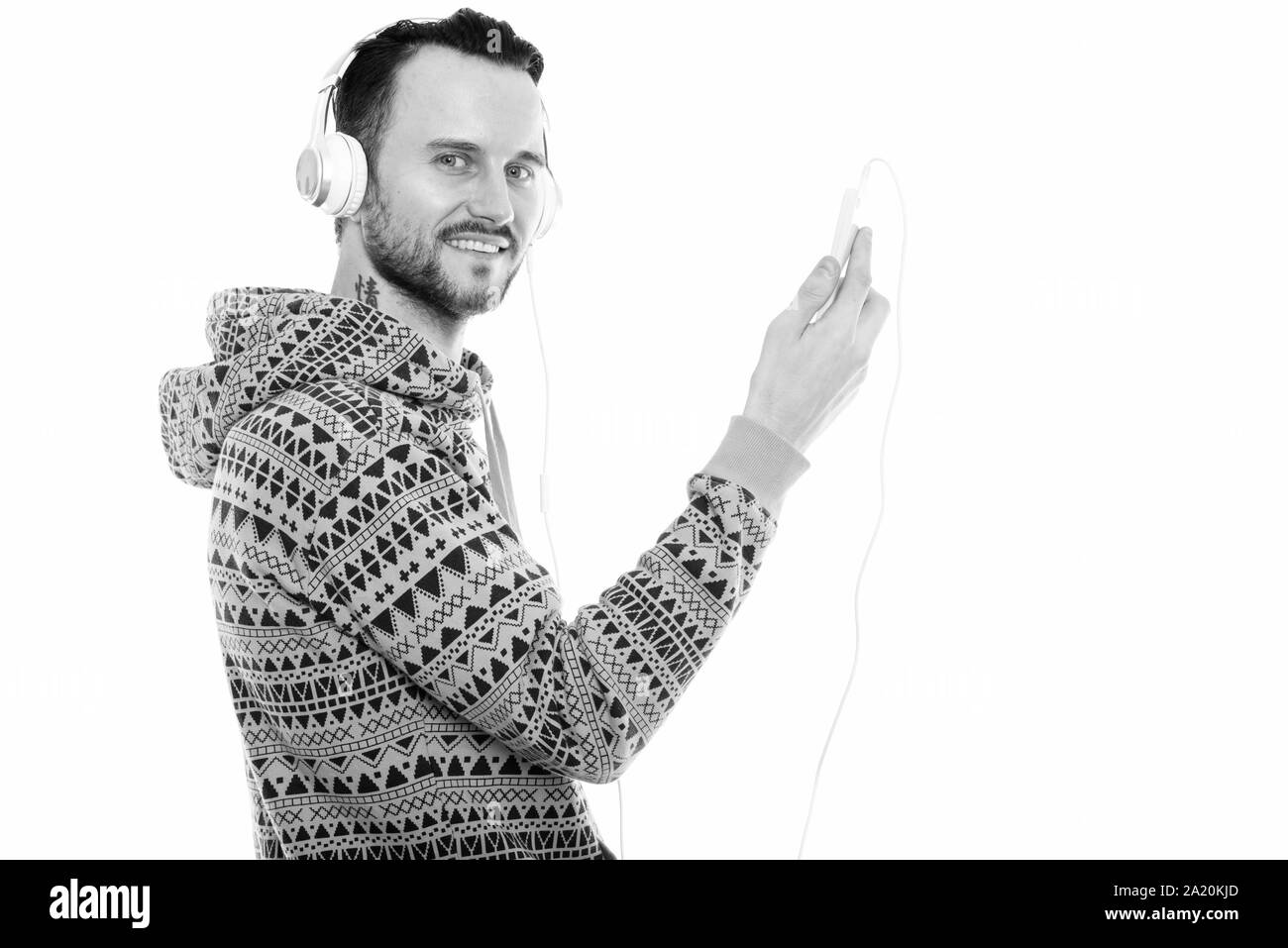 Portrait of happy young man smiling while holding mobile phone et écouter de la musique Banque D'Images