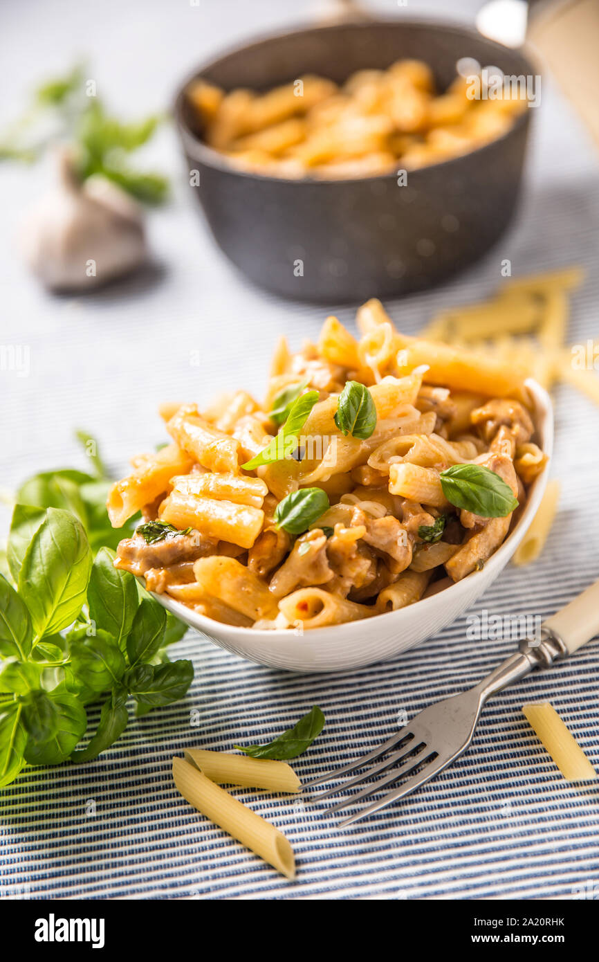 Les pâtes penne avec morceaux de poulet au basilic et parmesan champignons cuisine italienne dans un bol blanc sur la table de cuisine Banque D'Images