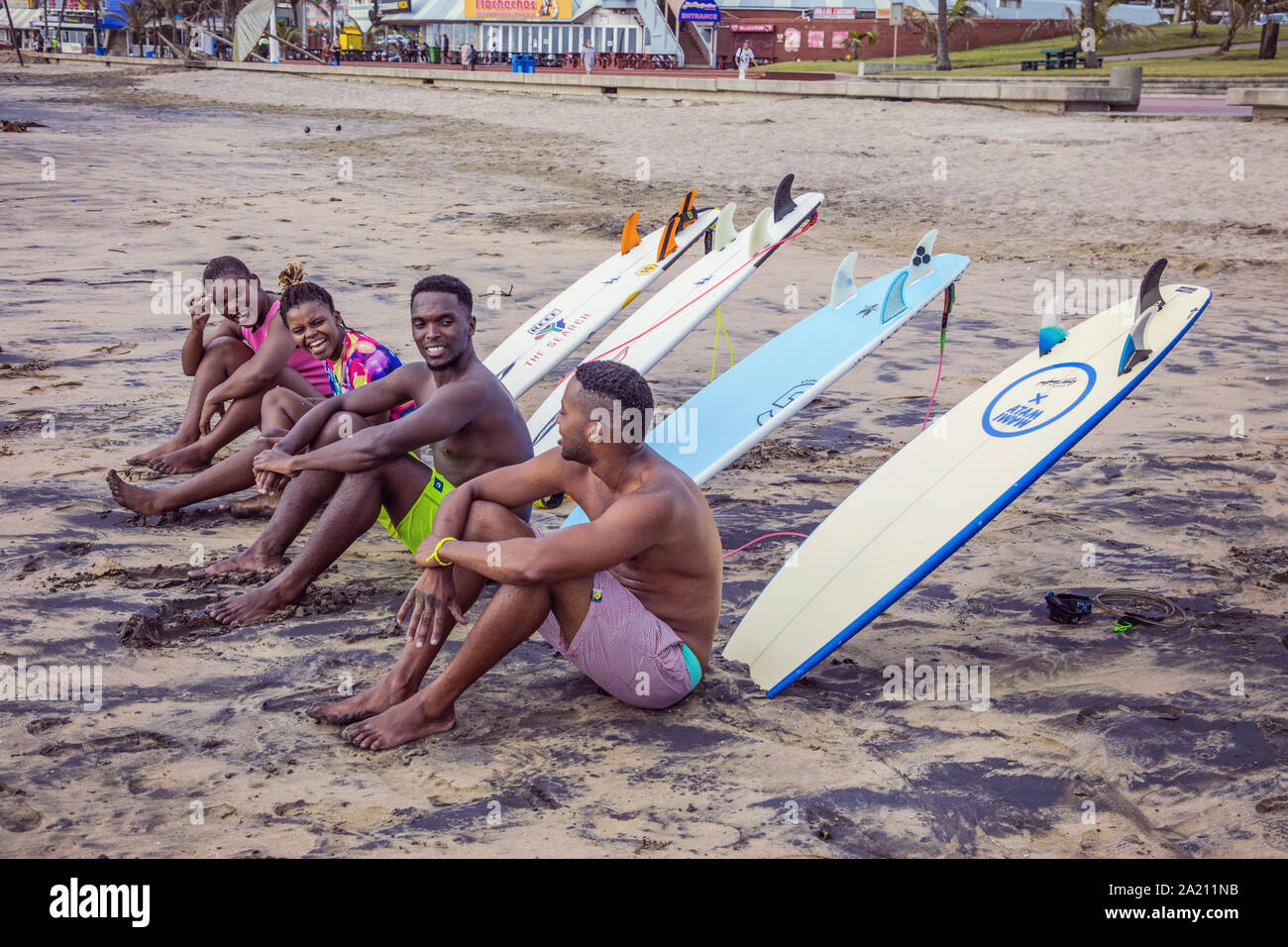 Des gens assis avec leurs planches de surf sur la plage de Durban Banque D'Images
