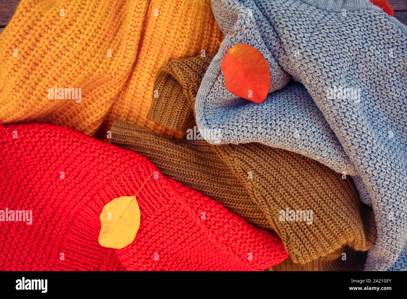 Un tas de choses en tricot de couleur différente et les feuilles d'automne. Banque D'Images