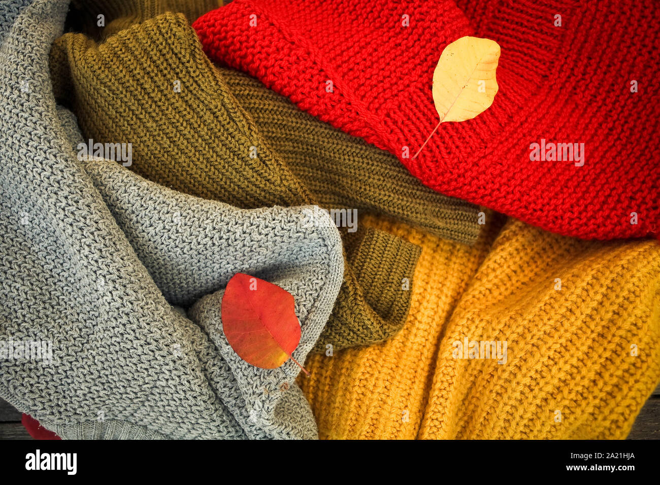 Un tas de choses en tricot de couleur différente et les feuilles d'automne. Banque D'Images