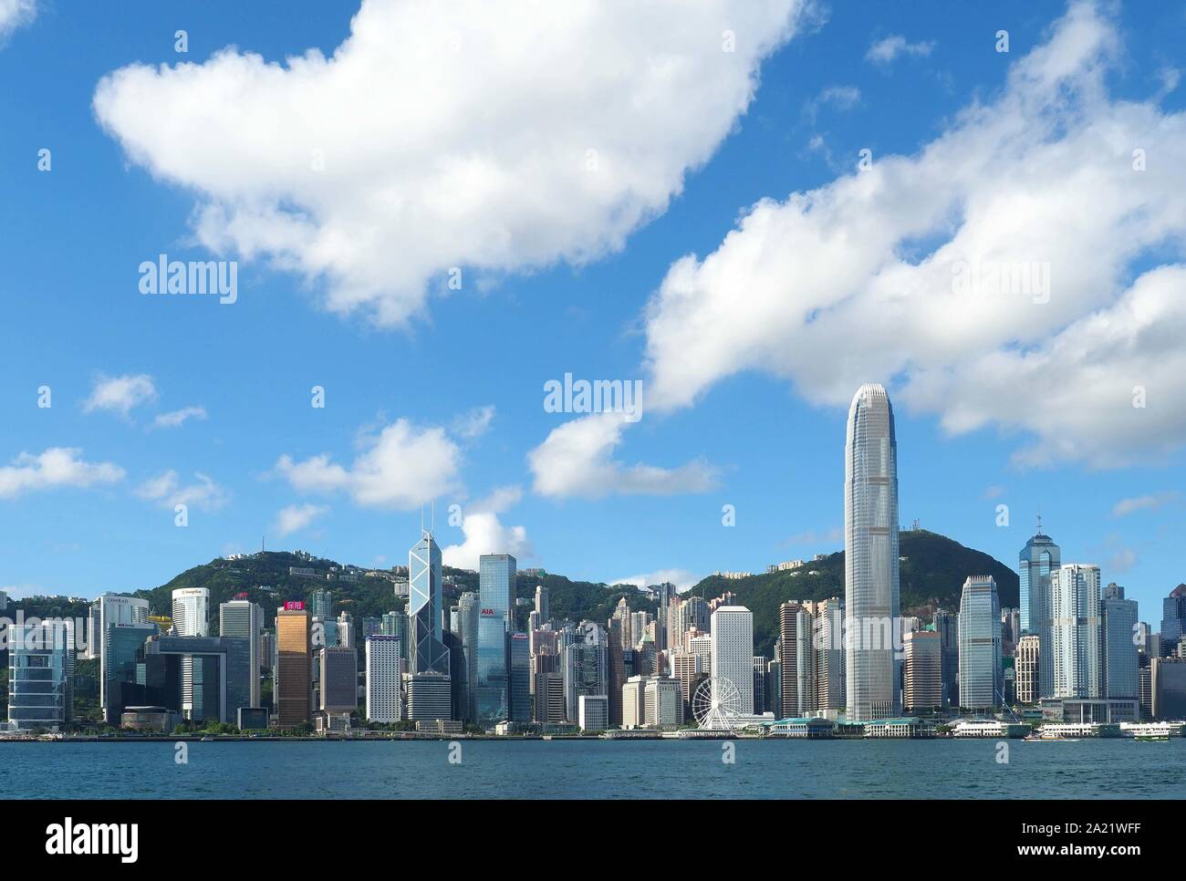 Un grand angle de vue sur le port de Hong Kong et les gratte-ciel de l'île de Hong Kong sous un ciel bleu avec des nuages blancs Banque D'Images