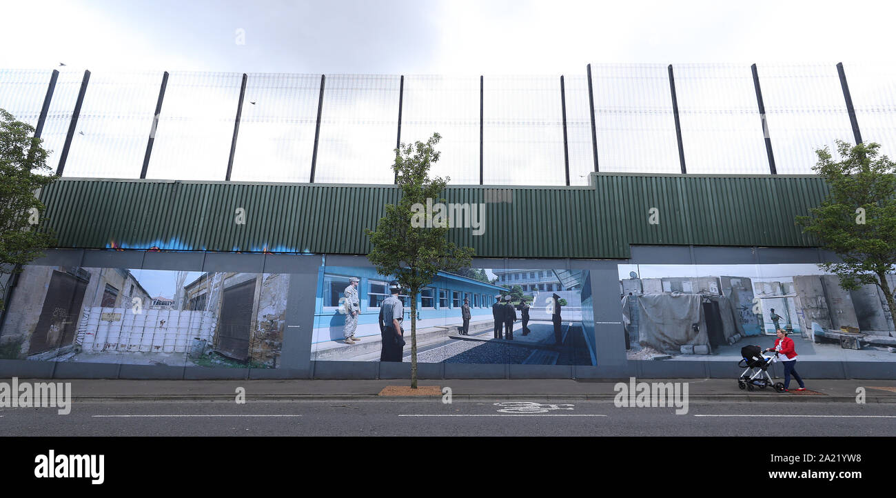 Une femme passe devant un mur de paix de Belfast qui expose des photos par photographe allemand Kai Wiedenhofer du monde ? ? ?s murs frontaliers, d'avance sur Brexit. Banque D'Images