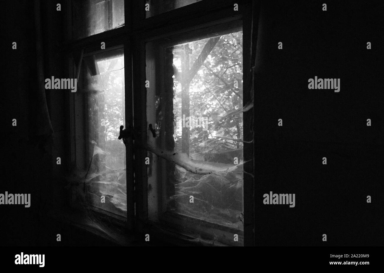 Toiles d'araignée à une vieille fenêtre d'une maison abandonnée en noir et blanc Banque D'Images