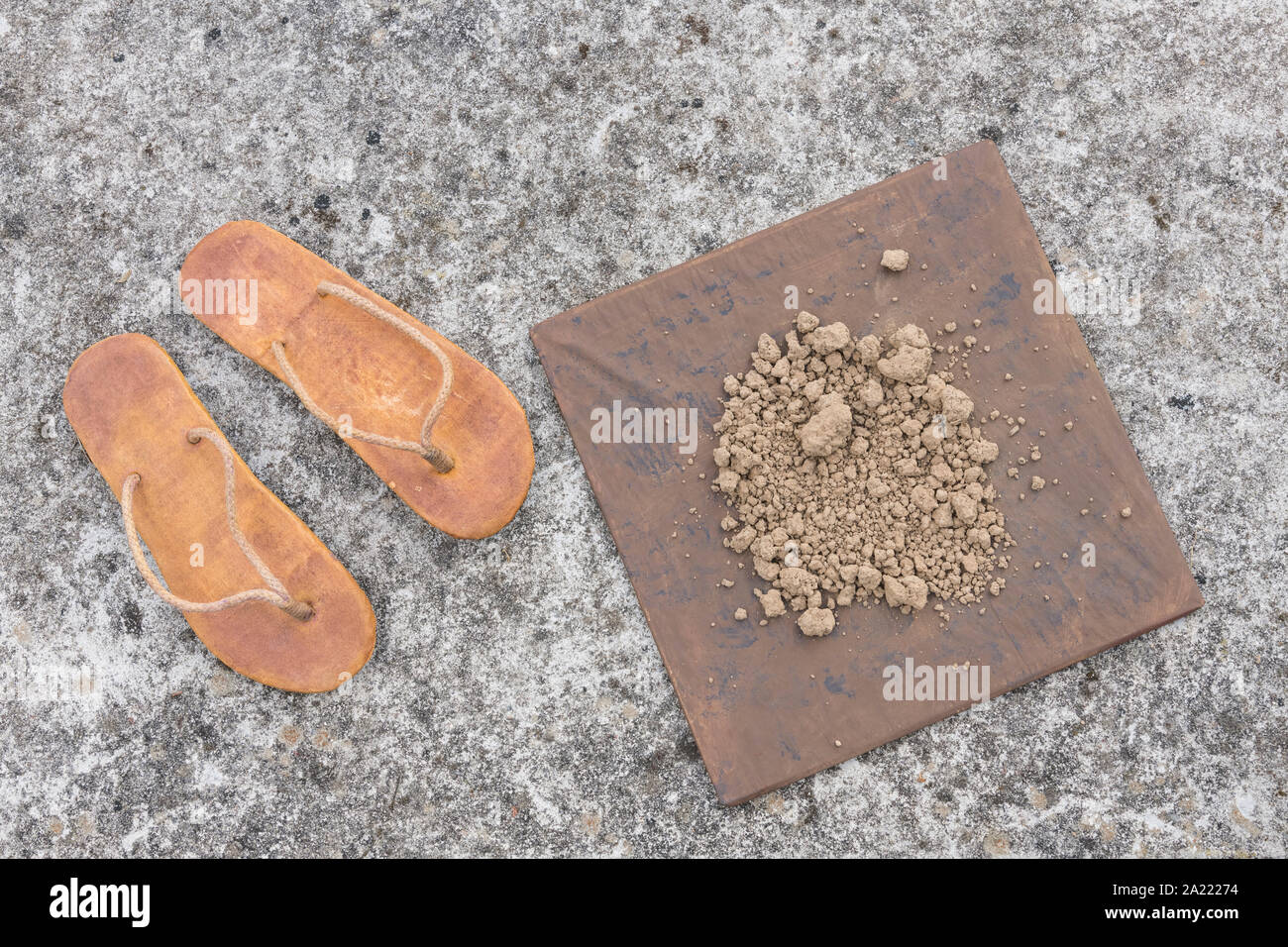 Flipflops hippy usés et carré avec la masse sur la surface du béton. La théorie de la terre plate métaphore, télévision earthers, théories du complot, preuve de la terre plate. Banque D'Images