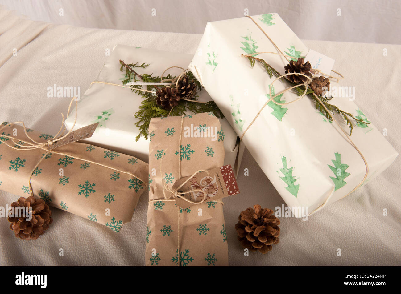 Des cadeaux de Noël enveloppé dans du papier cadeau durable en brun et  blanc avec impression verte. Noël fait maison se présente avec des  brindilles et vert de cocottes Photo Stock -