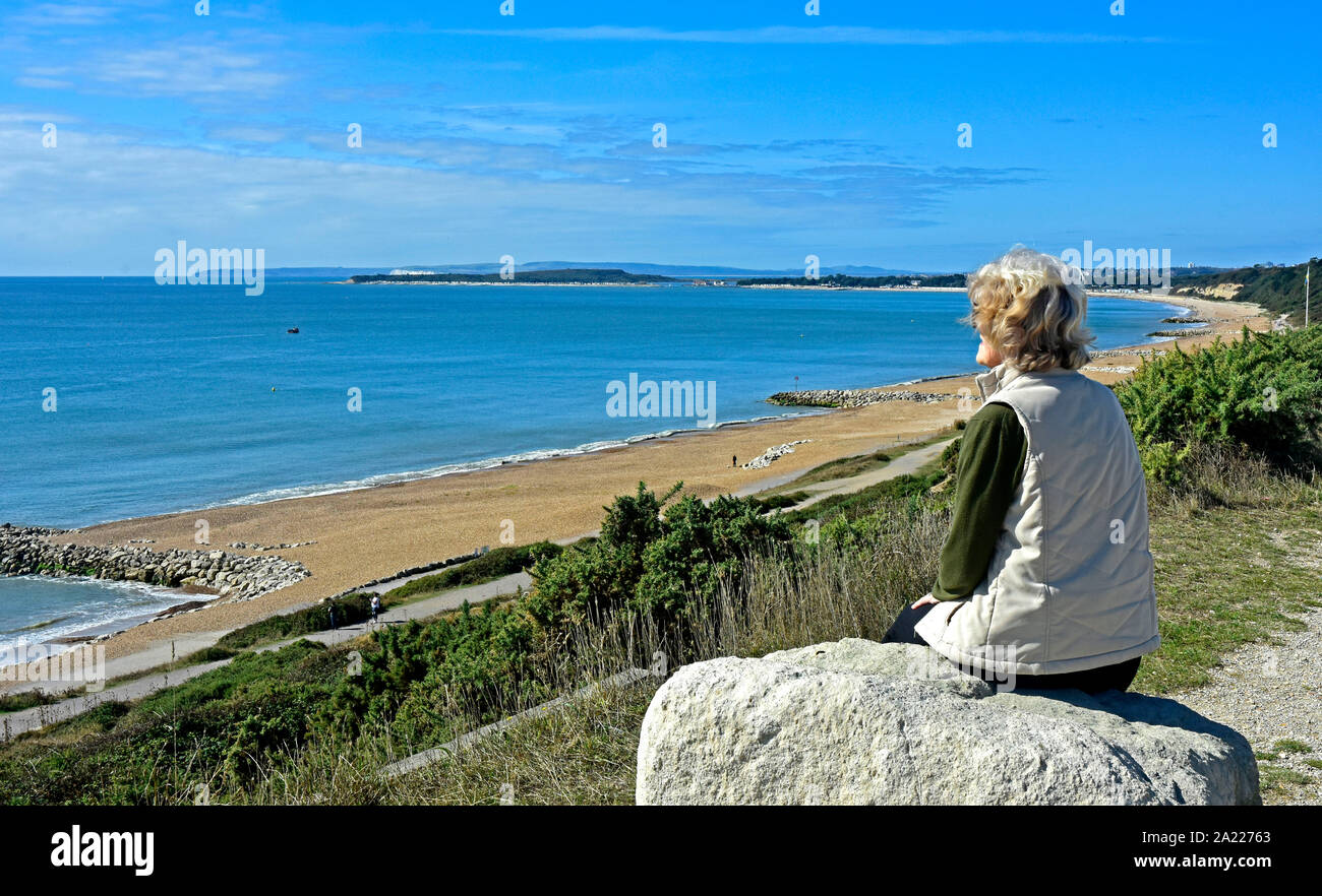 - Dorset Highcliffe - summertime - visiteur assis sur un rocher - profiter de la vue sur la baie - relaxing Banque D'Images