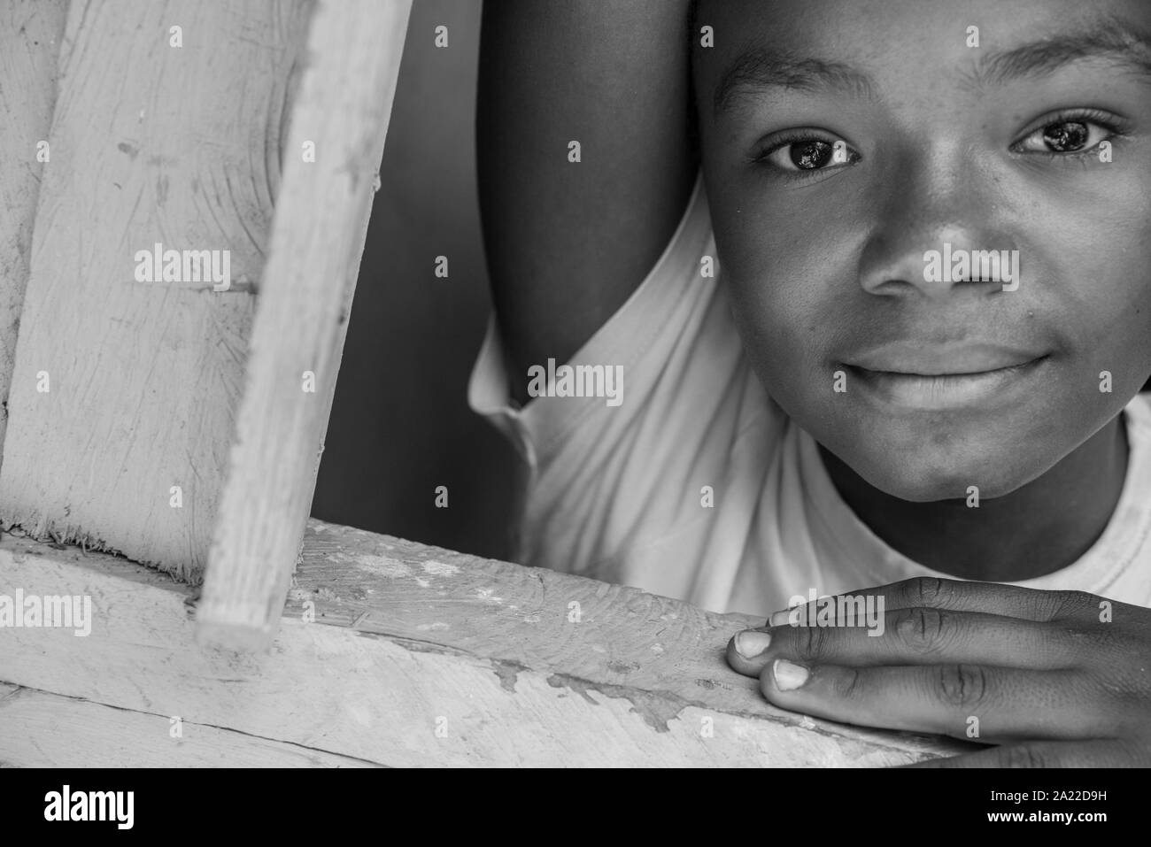 Fille afro-brésilien se penchant à la fenêtre de la chambre en bois Banque D'Images