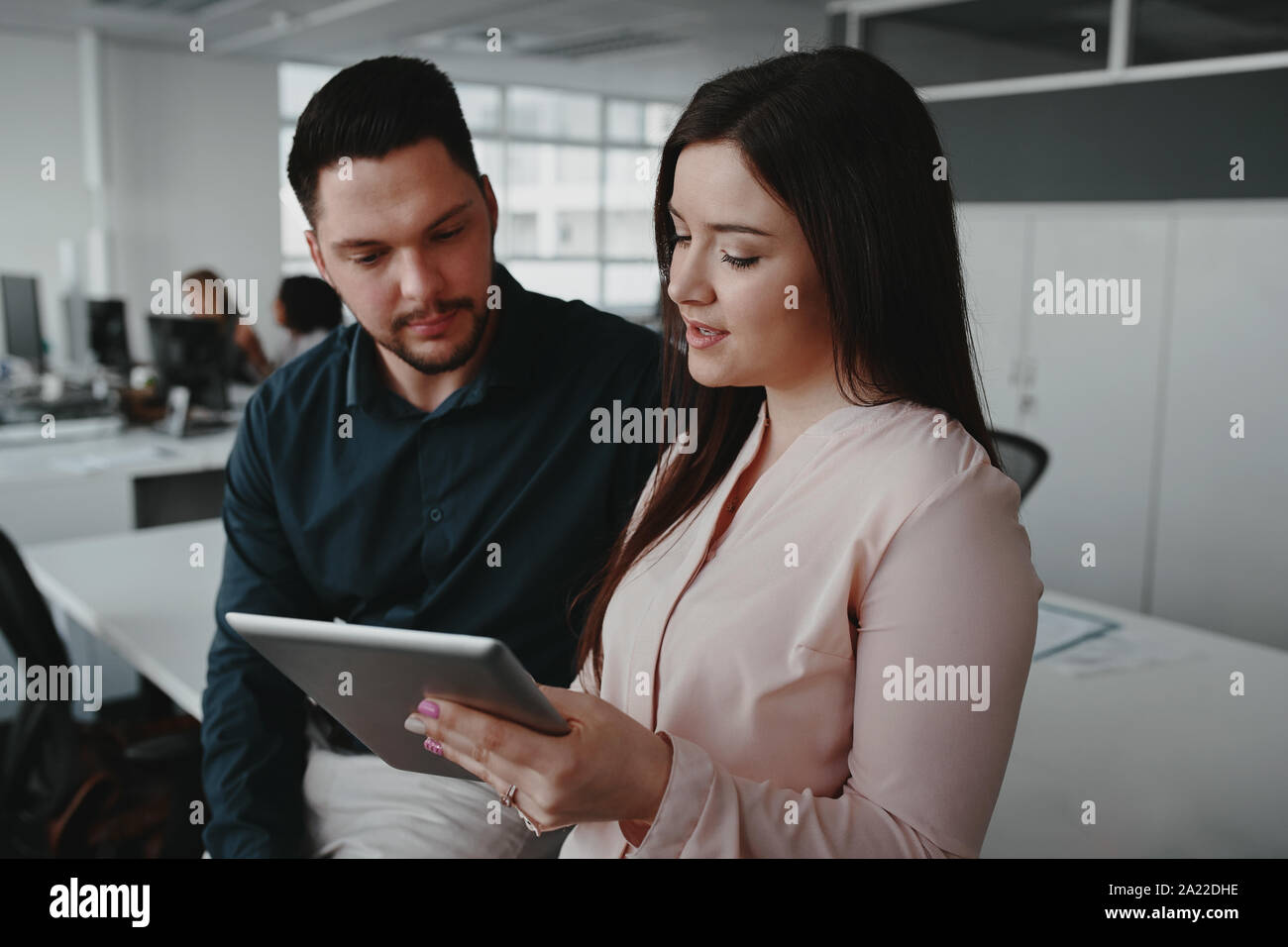 Smiling businesswoman montrant des données en ligne ou sur tablette numérique présentation à son collègue masculin Banque D'Images