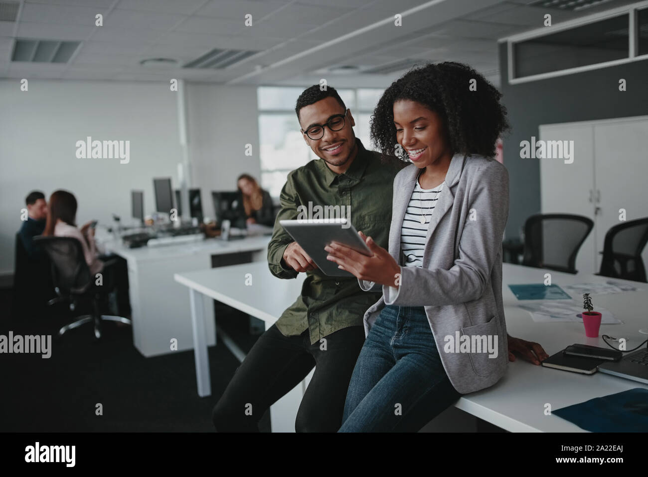 Deux succès african american young businesspeople sitting on desk using digital tablet in alors qu'au bureau Banque D'Images