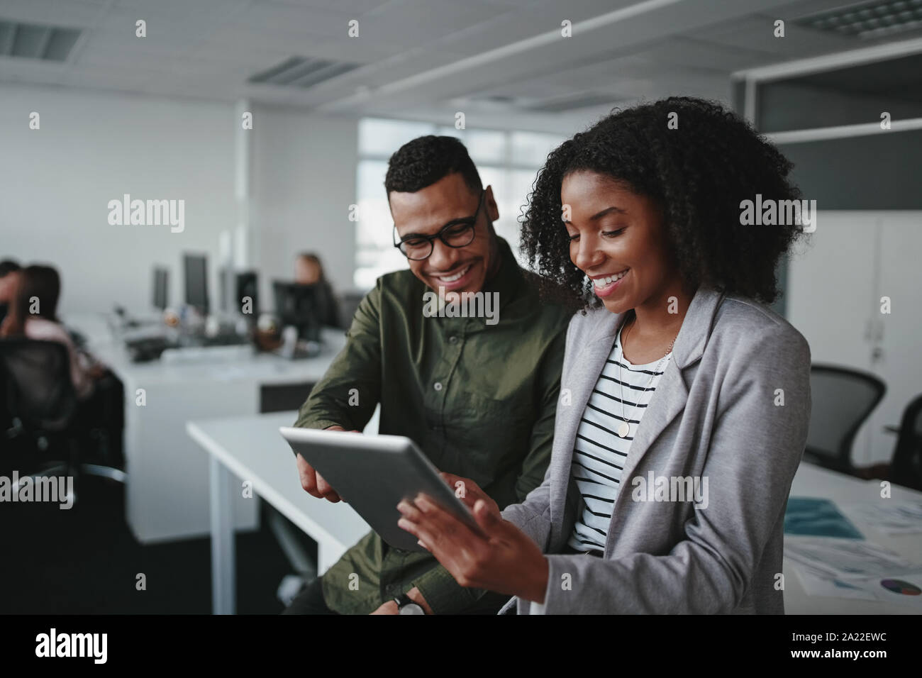 Smiling young african american businessman and businesswoman professionnels travaillant ensemble en ligne avec un digital tablet in office Banque D'Images