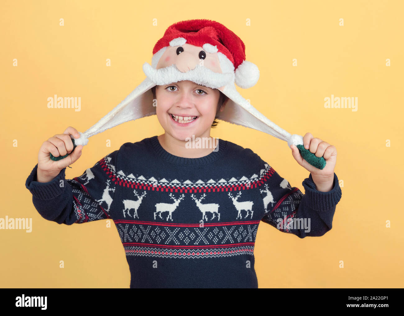 Smiling Child Wearing Christmas Santa Claus Hat sur fond jaune Banque D'Images