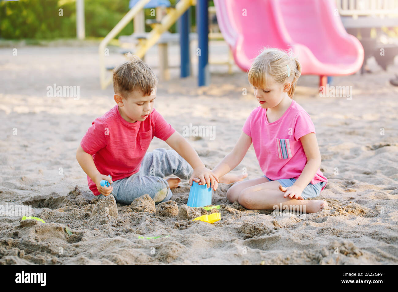 Les enfants d'âge préscolaire d'amis, garçons et filles, jouant avec le sable et les jouets dans sandbox sur journée d'été à l'extérieur. Enfance heureuse vie. Véritable authentique peop Banque D'Images