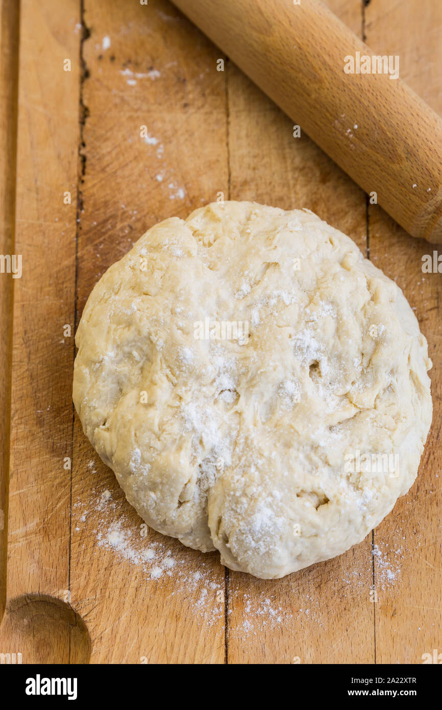 Matière première de la pâte avec un rouleau à pâtisserie sur une planche à découper Banque D'Images
