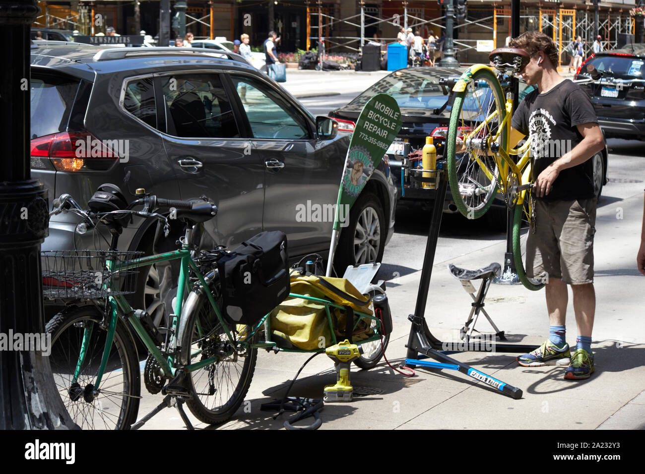 Man with mobile location de réparation de la réparation de vélo sur les trottoirs de la ville street Chicago Illinois Etats-Unis d'Amérique Banque D'Images