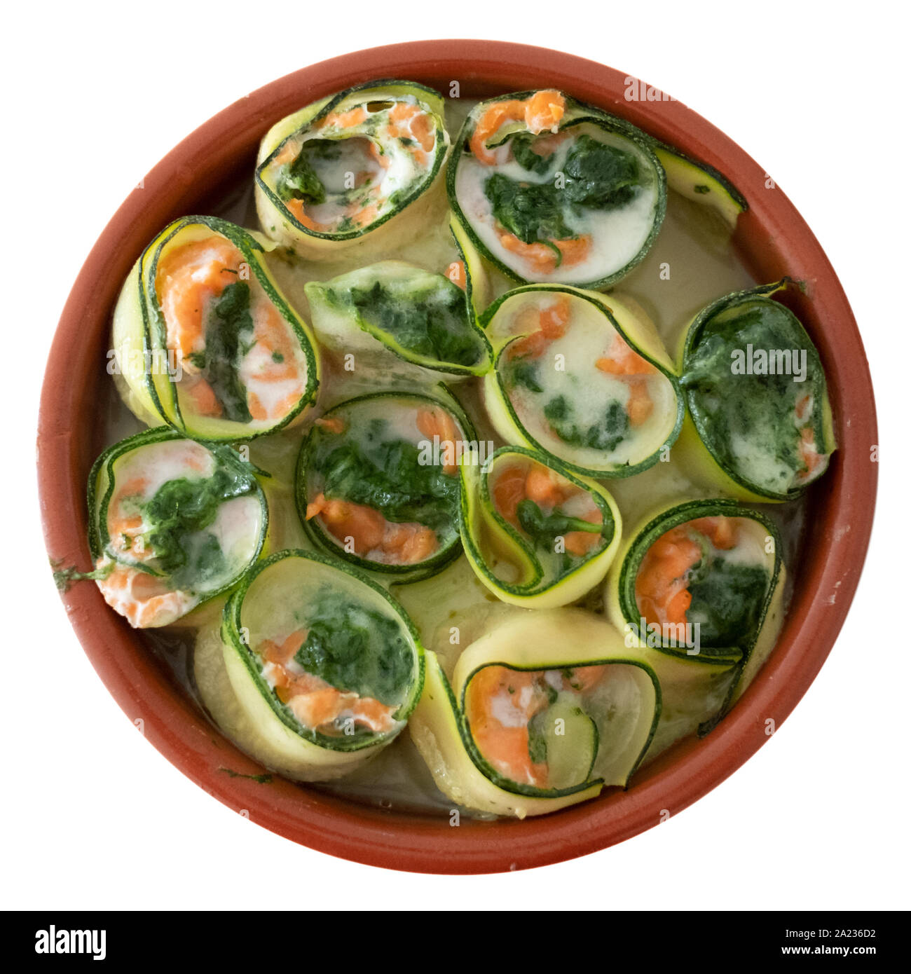 Plat de céramique ronde avec rouleaux de sushi cuit saumon - épinards et fromage mascarpone mélangé avec des rubans de courgettes roulées dans. Banque D'Images