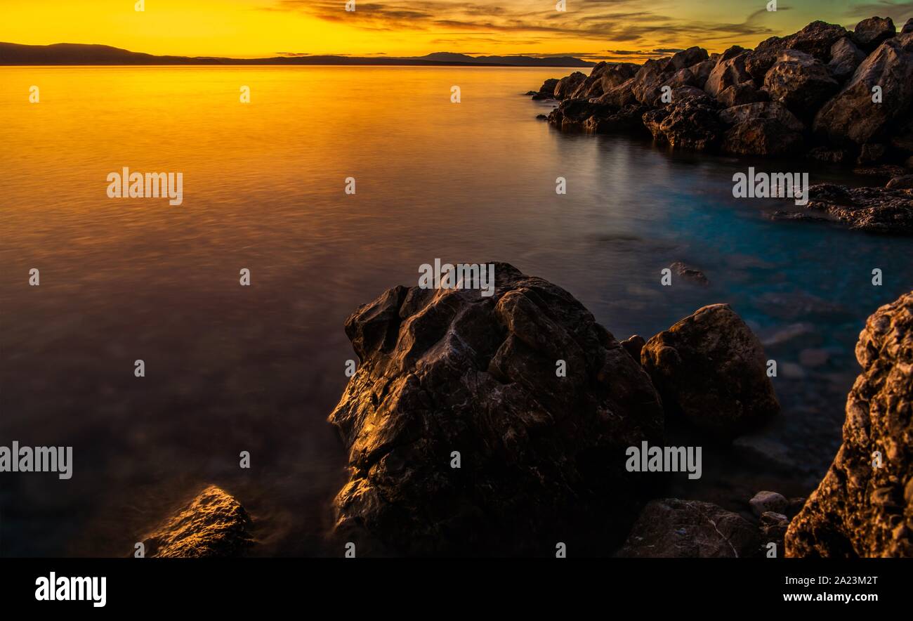 Mer panoramique Coucher de soleil avec des formations de roches sur la plage. Coloré Crépuscule. Banque D'Images