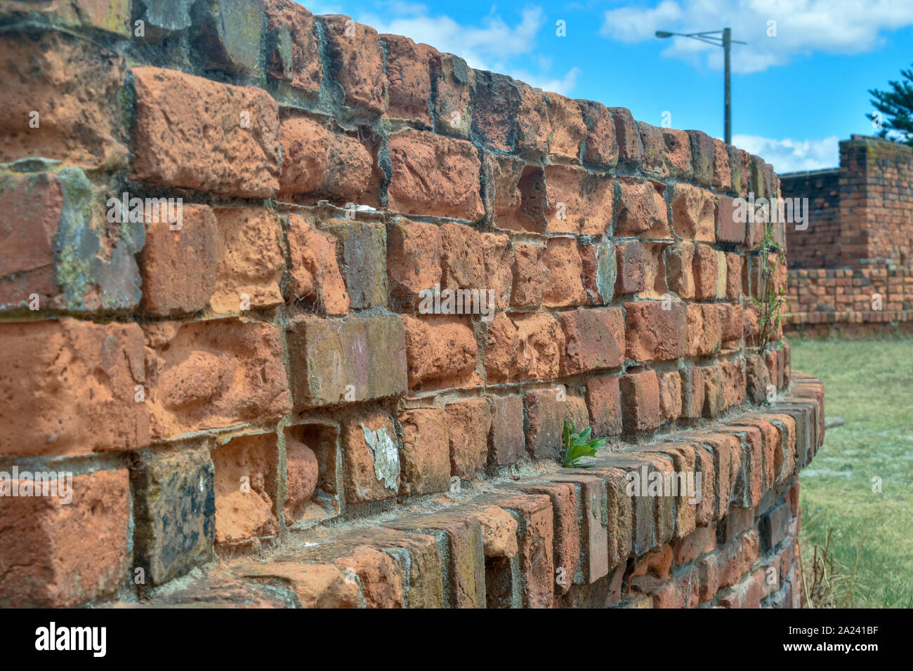 Un mur de brique rouge à l'écart des courbes vers un autre mur à l'arrière-plan Banque D'Images