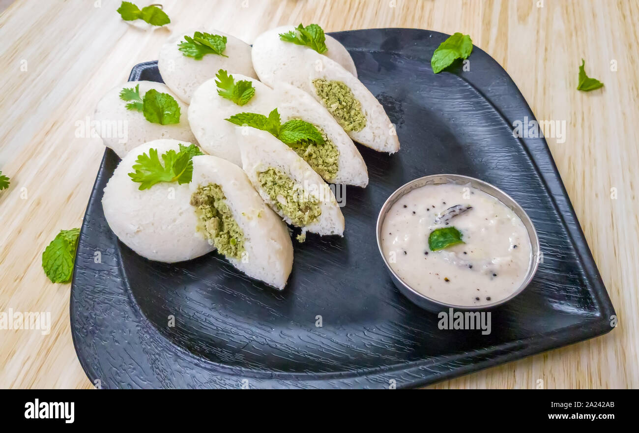 Idlis vapeur farci de viande hachée de poulet avec les feuilles de menthe avec chutney de noix de coco blanche dans une plaque noire Banque D'Images