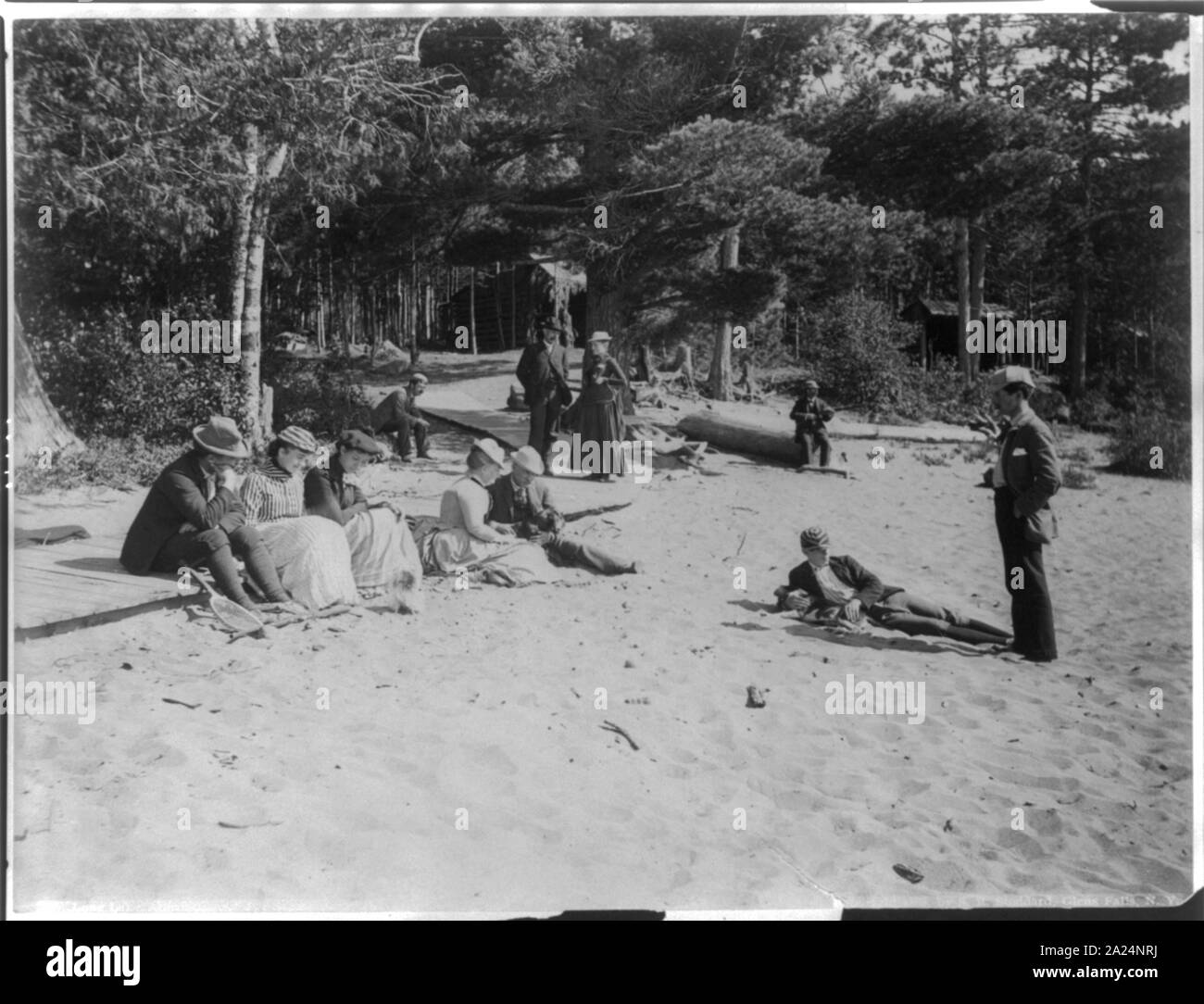 Les gens se détendre sur une plage de sable, à l'Adirondack mts., N.Y. ; appentis dans backgrd Banque D'Images