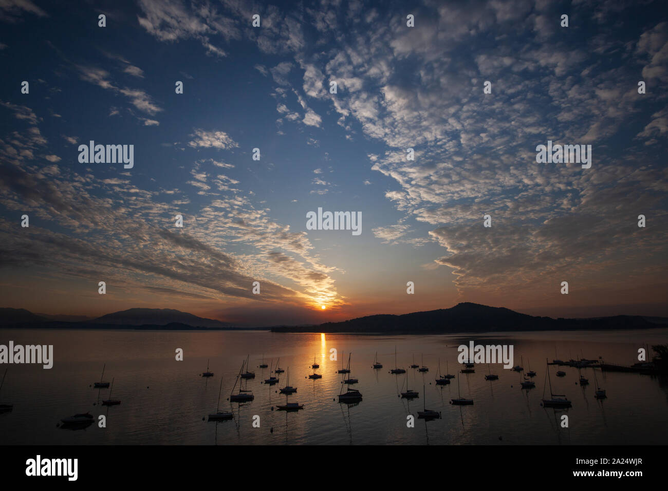 Matin lever du soleil sur un grand lac de montagne avec de nombreux bateaux nuages et réflexions. Banque D'Images