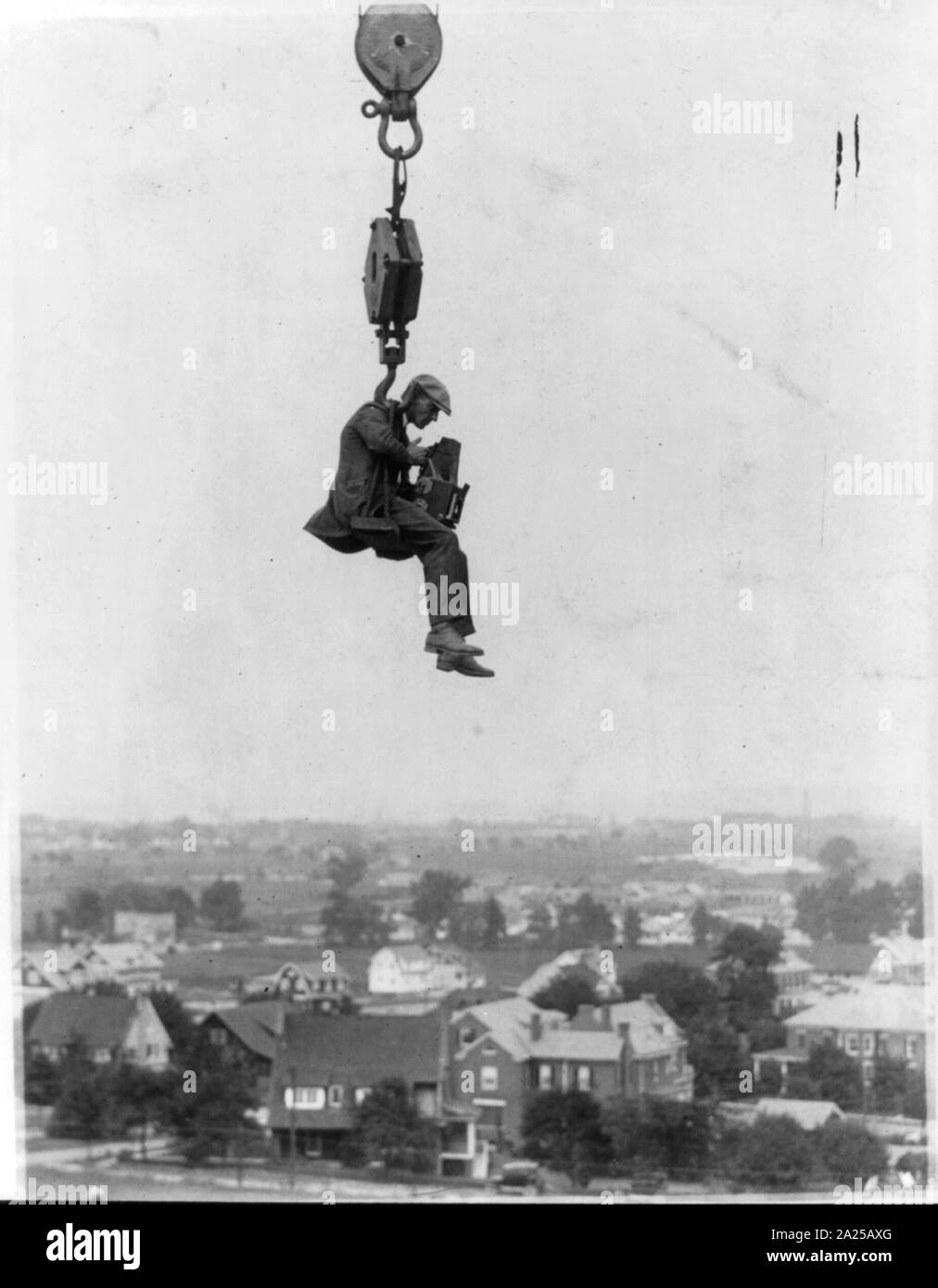 Photographe avec appareil photo suspendu du crochet d'une grue (haut) dans l'air Banque D'Images