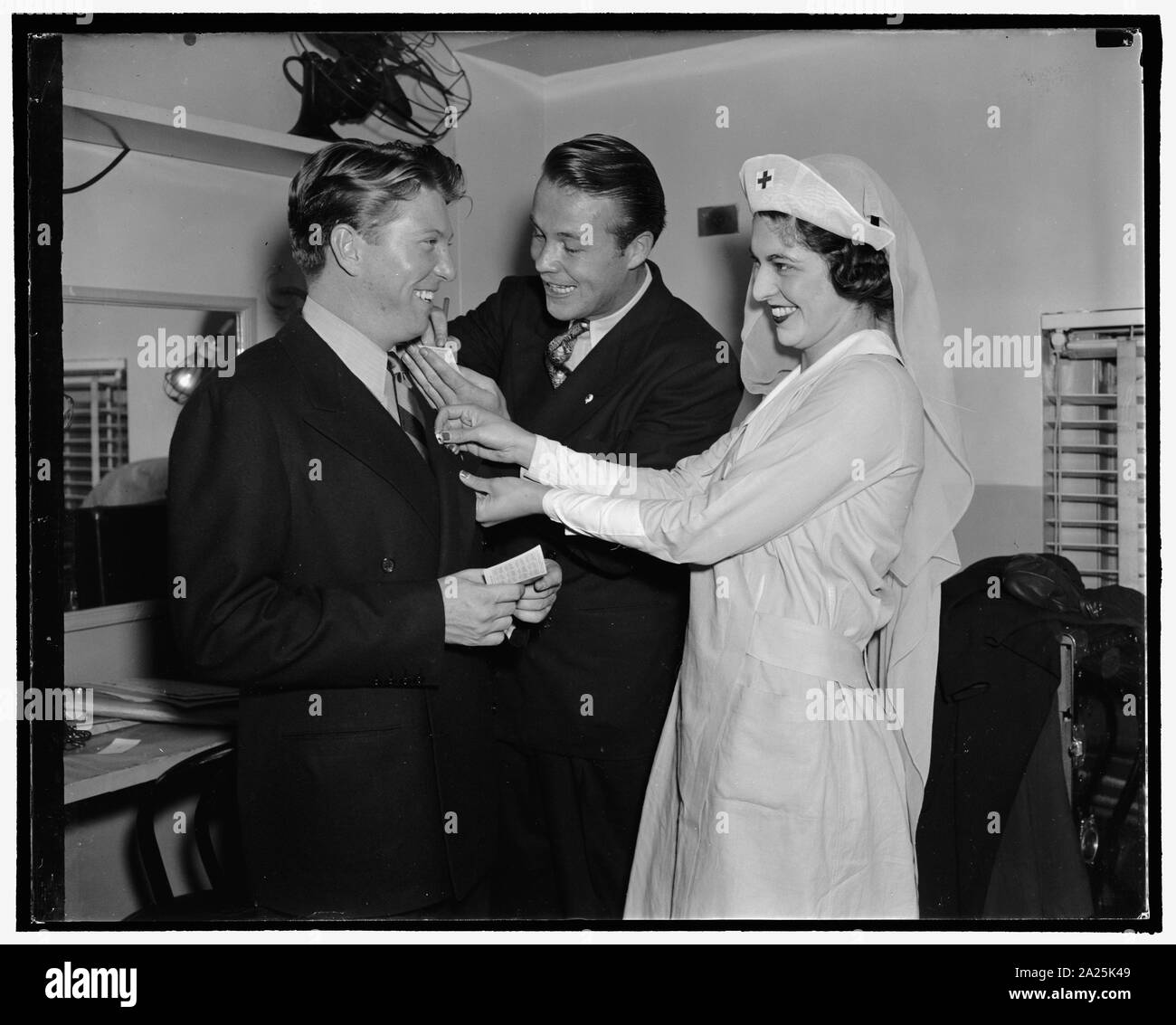 Photo stars s'inscrire à la Croix Rouge. Entre les apparitions au théâtre Earle Johnny Davis, (à gauche) et Wayne Morris reçoivent leur croix rouge de broches de Mlle Carolyn Chantry, Fille du Capitaine Allan USN et Mme Chantry Chantry, 28/09/38 Banque D'Images