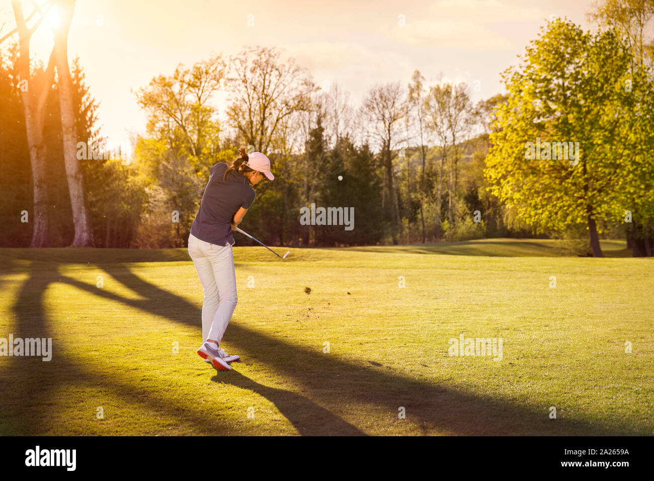 Joueur de golf féminin au coucher du soleil. Banque D'Images