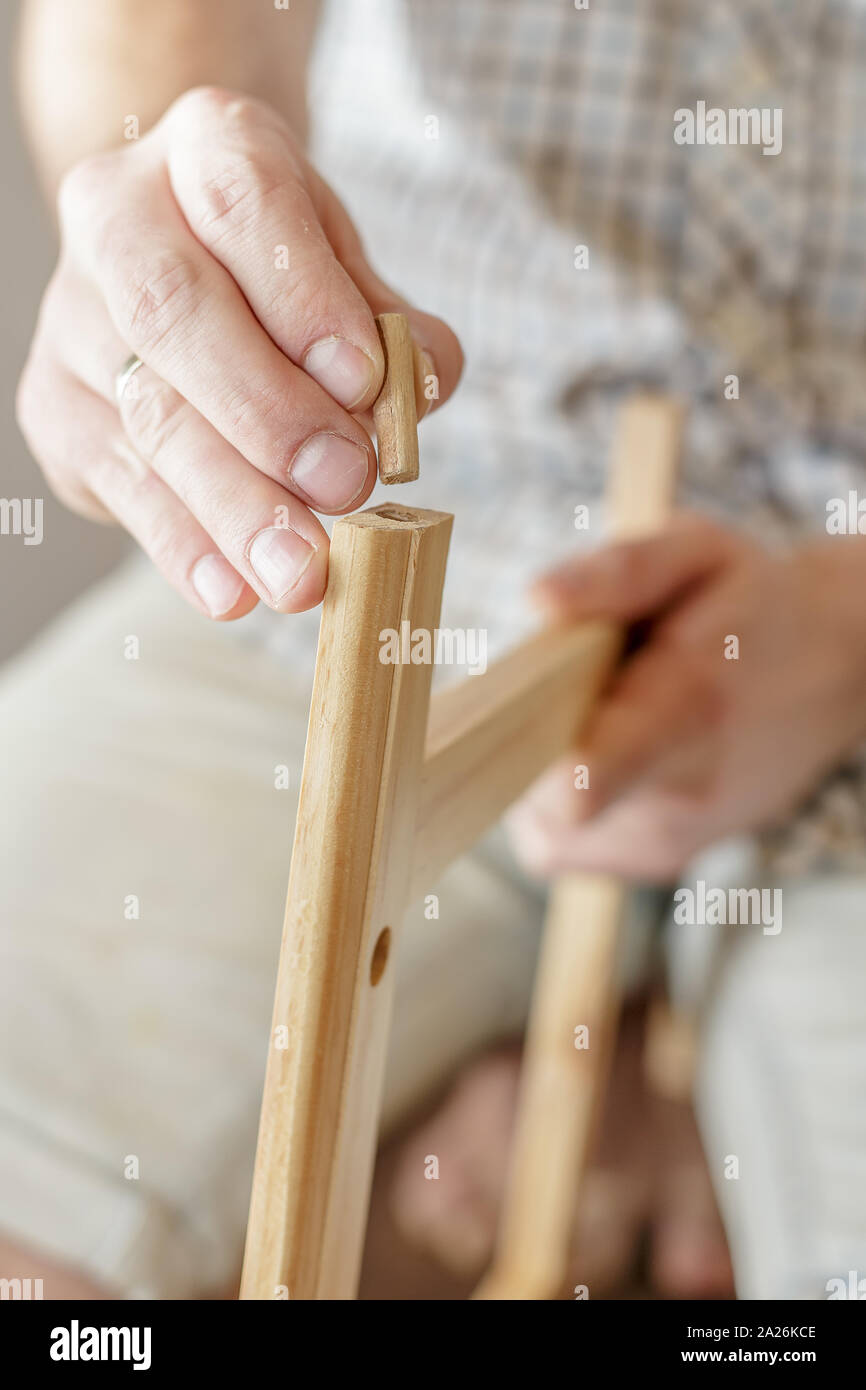 L'homme insère une cheville de bois dans un morceau de bois, close-up Banque D'Images