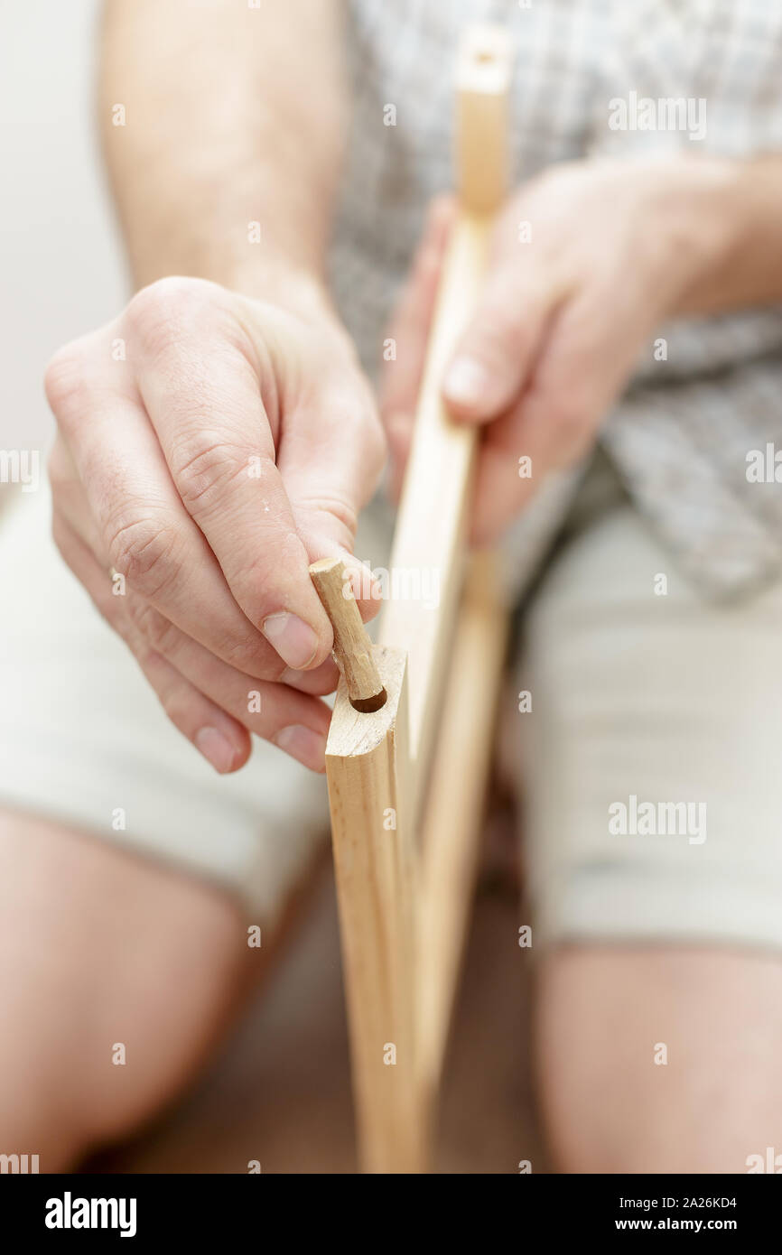 L'homme insère une cheville de bois dans un morceau de bois, close-up Banque D'Images