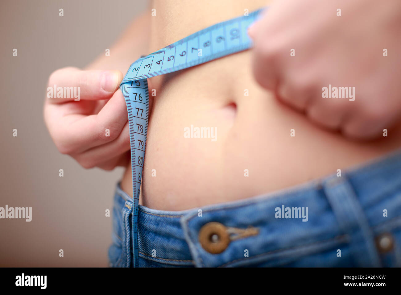 À peau claire, la femme en bleu jeans est mesurée à l'aide d'un ruban belle taille fine Banque D'Images