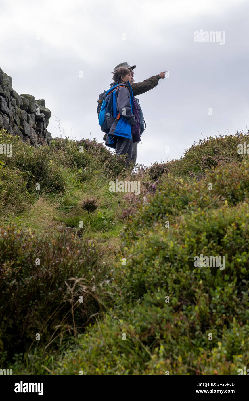 Deux promeneurs contempler la vue sur un sentier près de la Pennine Way, près de Stanbury du West Yorkshire. Banque D'Images