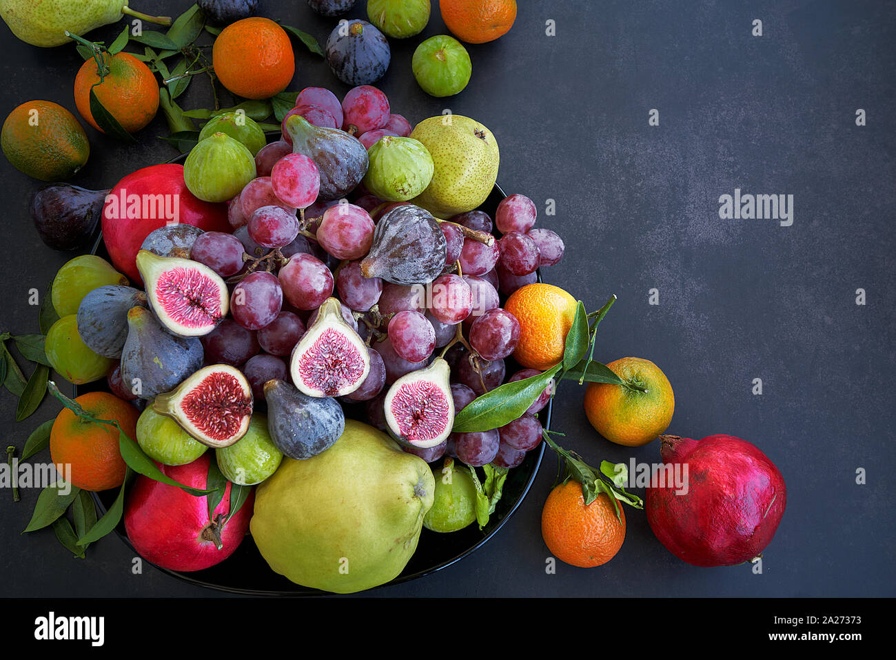 Vue aérienne des fruits sur un fond sombre. Violette et verte figues, raisins, grenades, les poires et les oranges. Banque D'Images