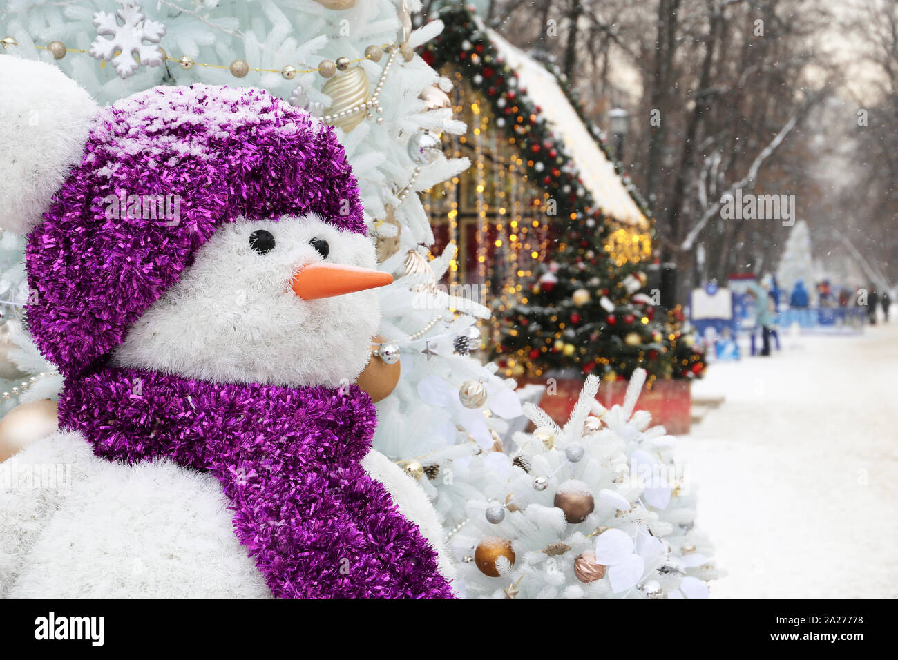 Bonhomme de neige sur une rue d'hiver, les décorations de Noël dans la ville. Fête du nouvel an au cours de la neige Banque D'Images