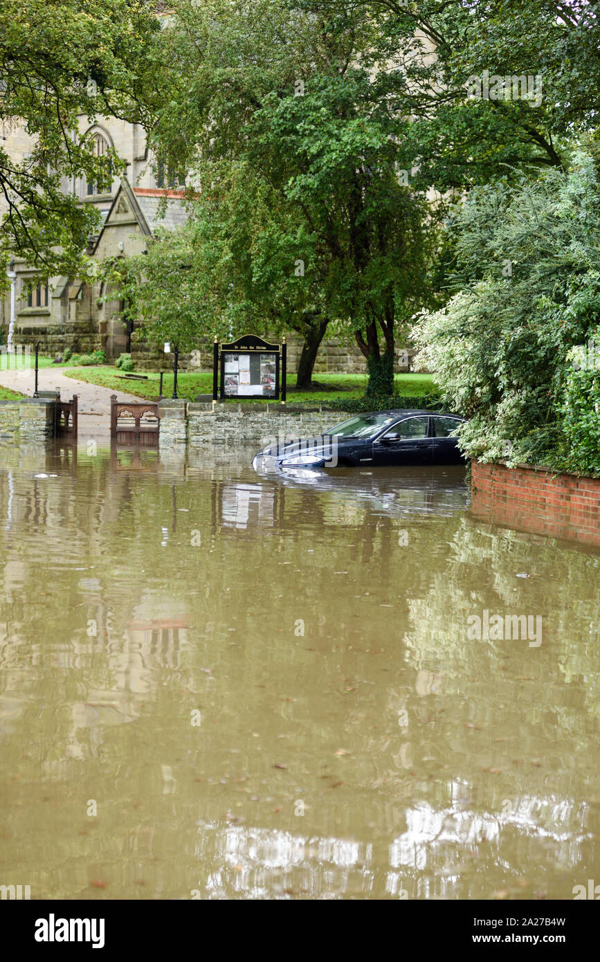 Colston Bassett, Dorset, UK : 01 octobre 2019. Frappe de la rivière qui traverse les Alpes village de Colston Bassett éclater ses banques l'inondation sur la porte à l'Église en détresse véhicules laissant. Banque D'Images