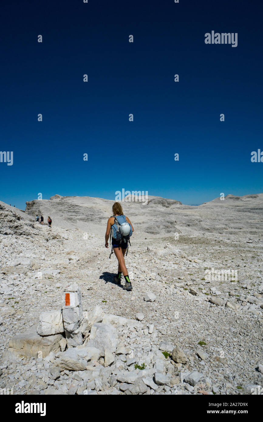 Alpiniste féminine à travers des randonnées sauvages un désert rocheux du plateau de haute montagne dans les Dolomites après une dure ascension Banque D'Images