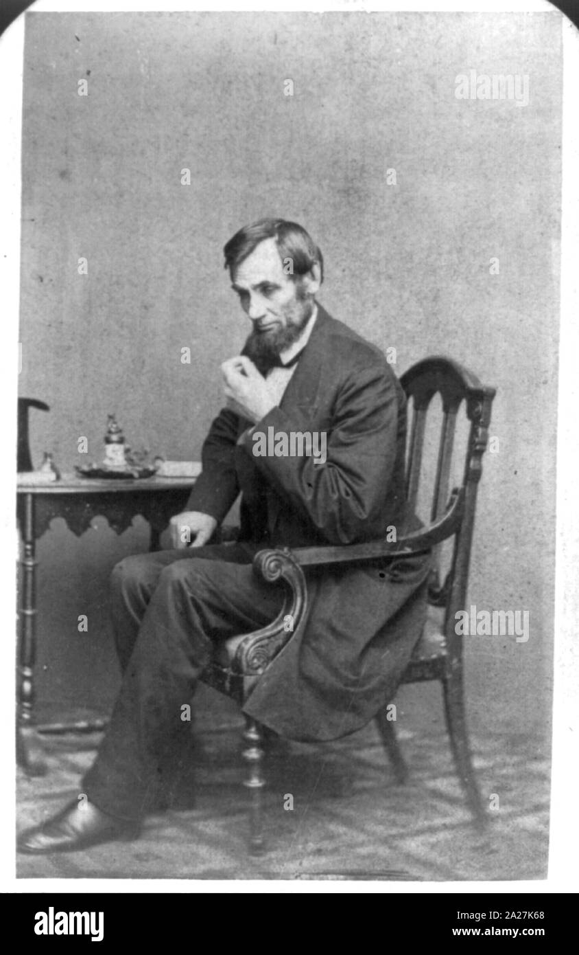 Le président Abraham Lincoln, assis à côté d'une petite table, dans une pose de réflexion Banque D'Images