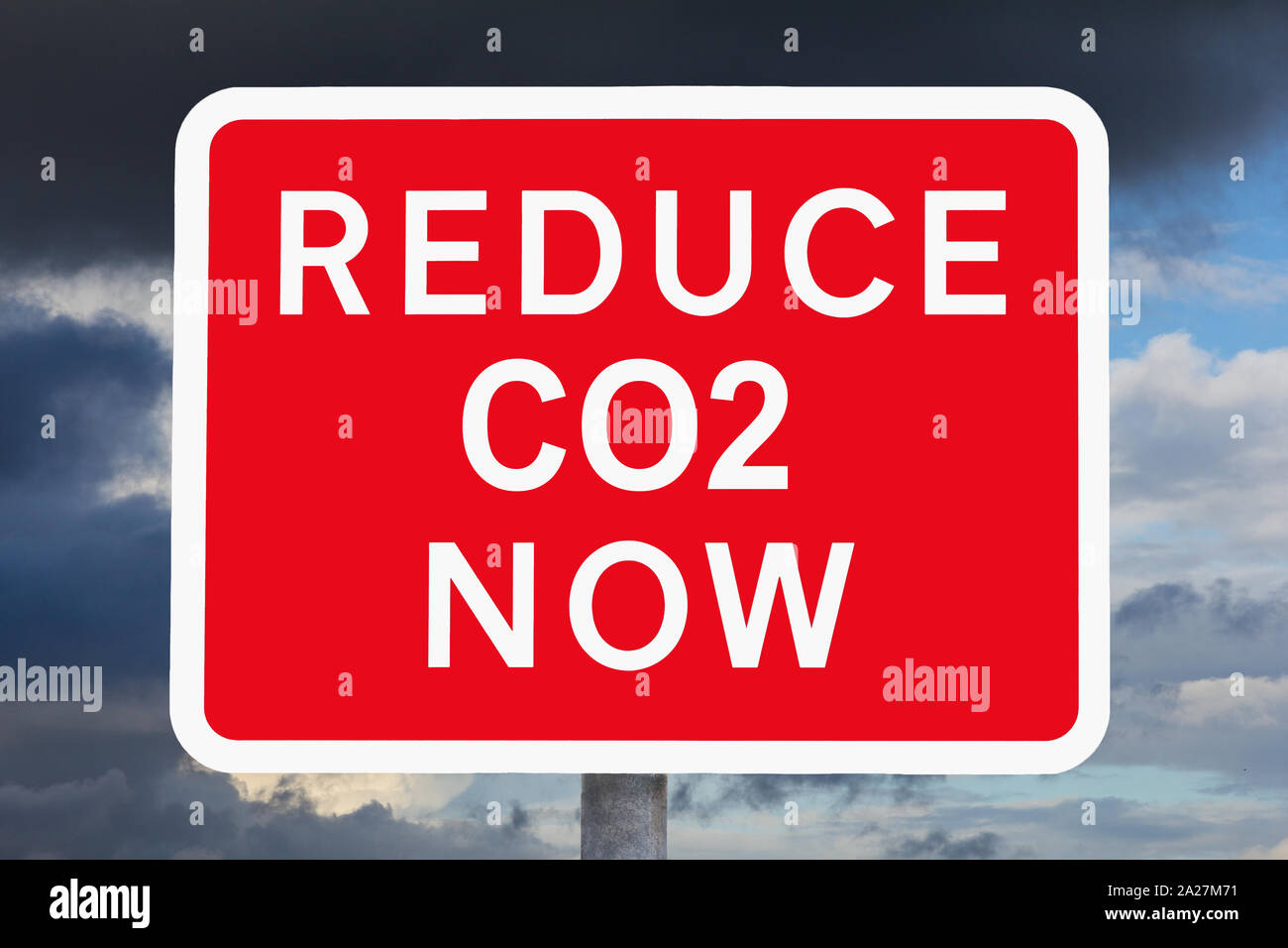 Notion de changement climatique : réduire les émissions de CO2 est à présent texte sur panneau d'avertissement rouge et blanc en face de ciel sombre. Banque D'Images