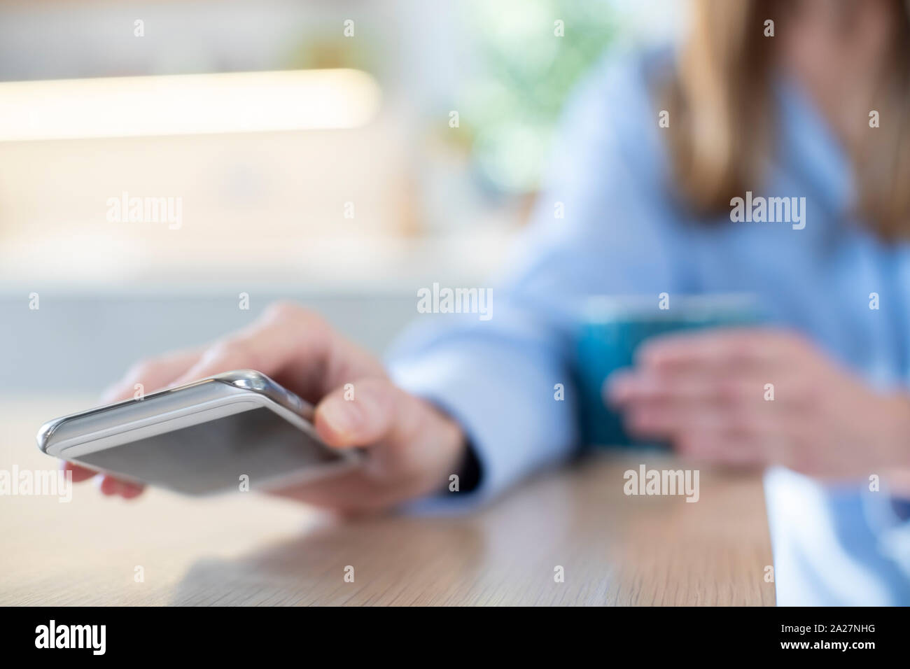 Femme inquiète de l'utilisation excessive des médias sociaux portant sur téléphone mobile sur la table Banque D'Images