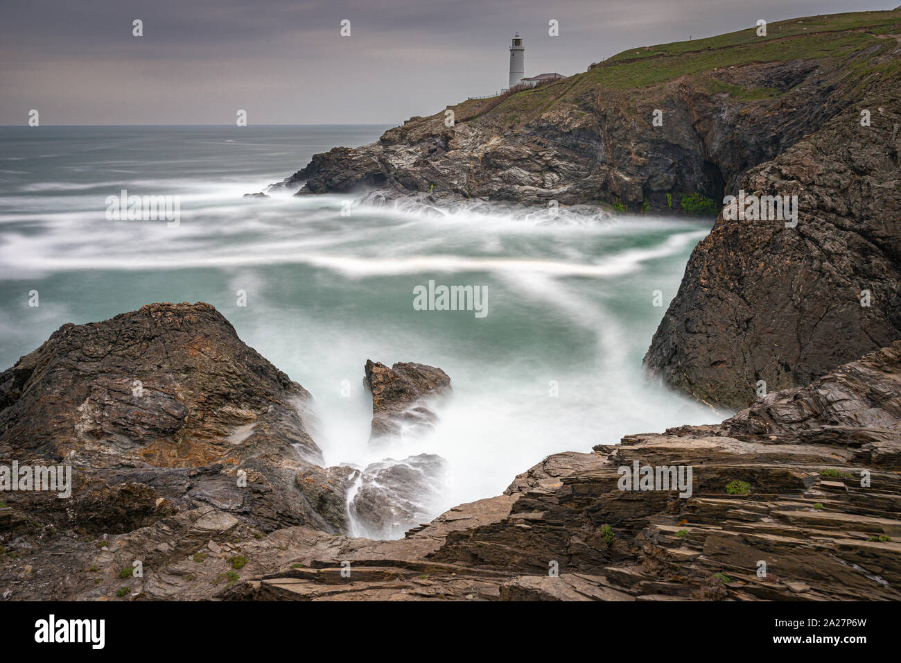 Trevose Head Lighthouse en Cornouailles du Nord avec un ciel d'orage et des vagues se brisant sur les rochers fait un beau paysage sauvage Banque D'Images
