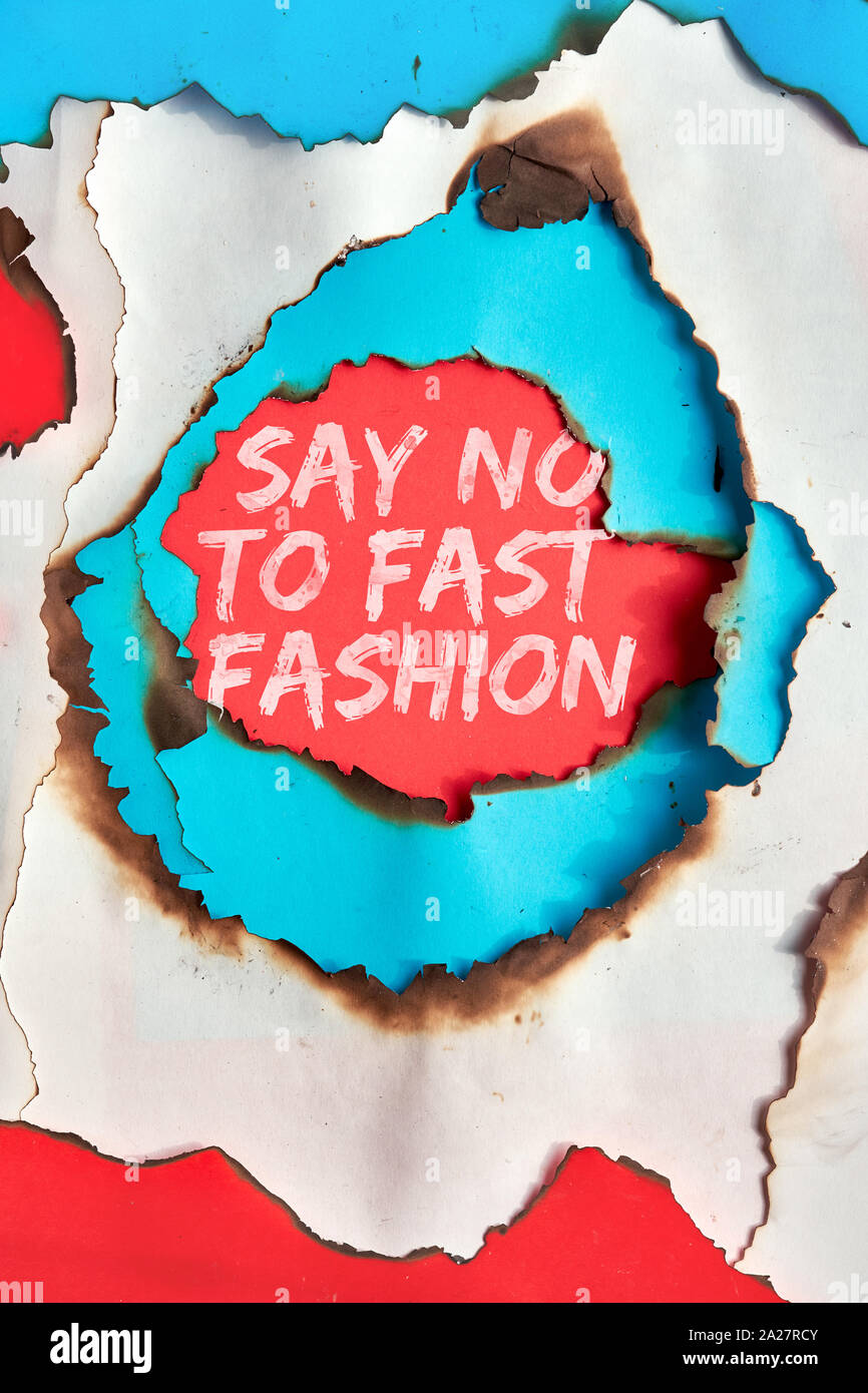 Texte 'Say no pour fast fashion' dans le trou brûlé si blanc, rouge et du papier turquoise Banque D'Images