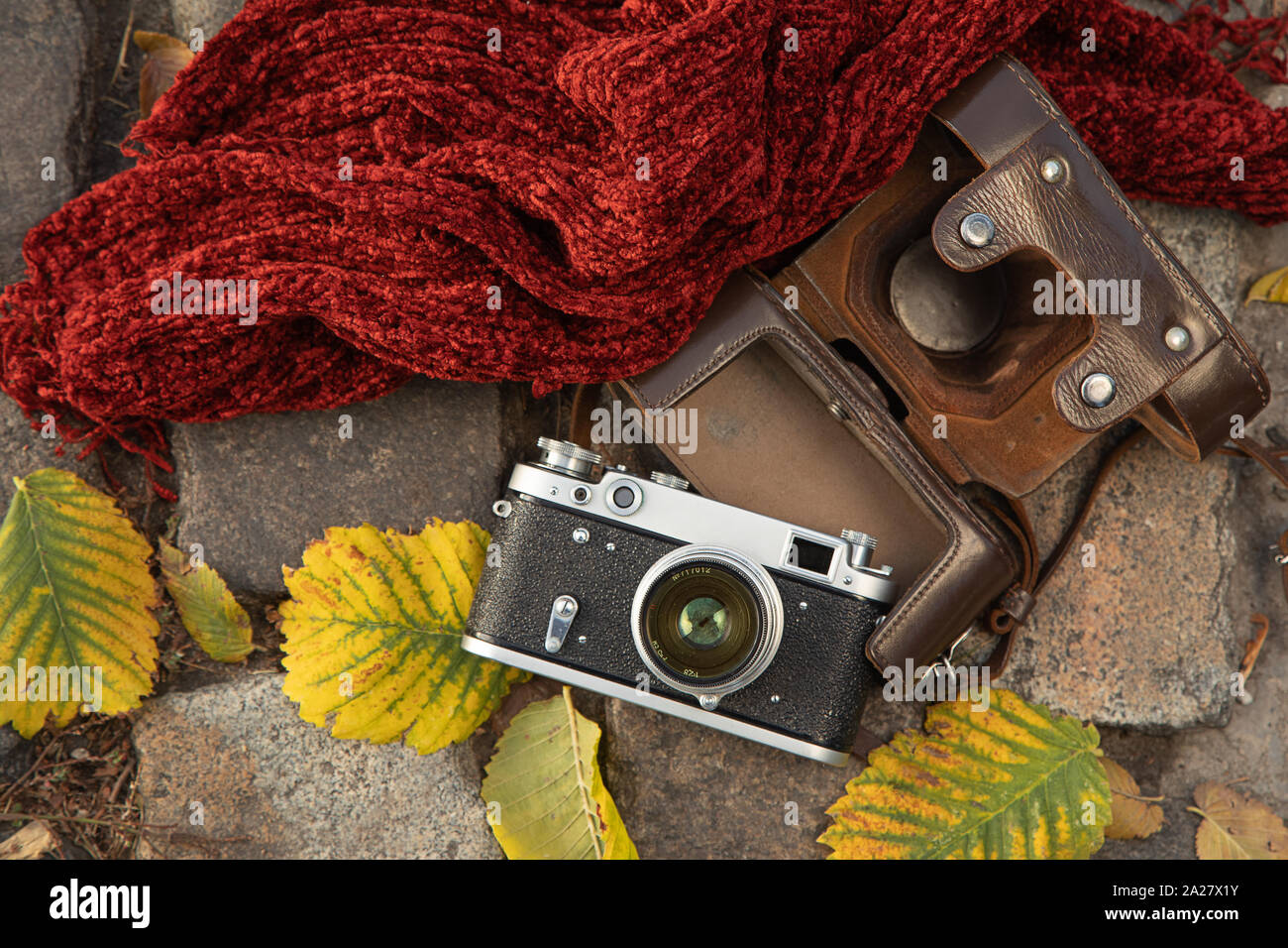 Humeur d'automne still life : télémètre vintage camera, 7290, en cuir marron, foulard rouge et les feuilles portant sur la chaussée Banque D'Images