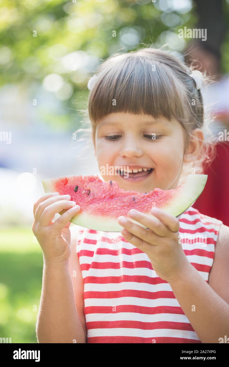 Bonnes vacances - belle little girl eating watermelon sur une pelouse verte Banque D'Images