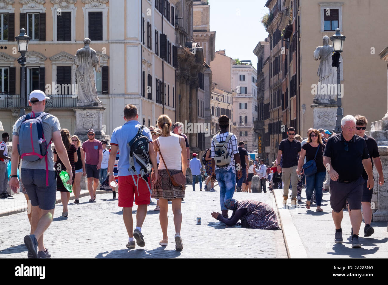 Personnes âgées femme mendiant à genoux au milieu de la foule des touristes sur le pont en direction de la Cité du Vatican. Marché autour et ignorés. Banque D'Images