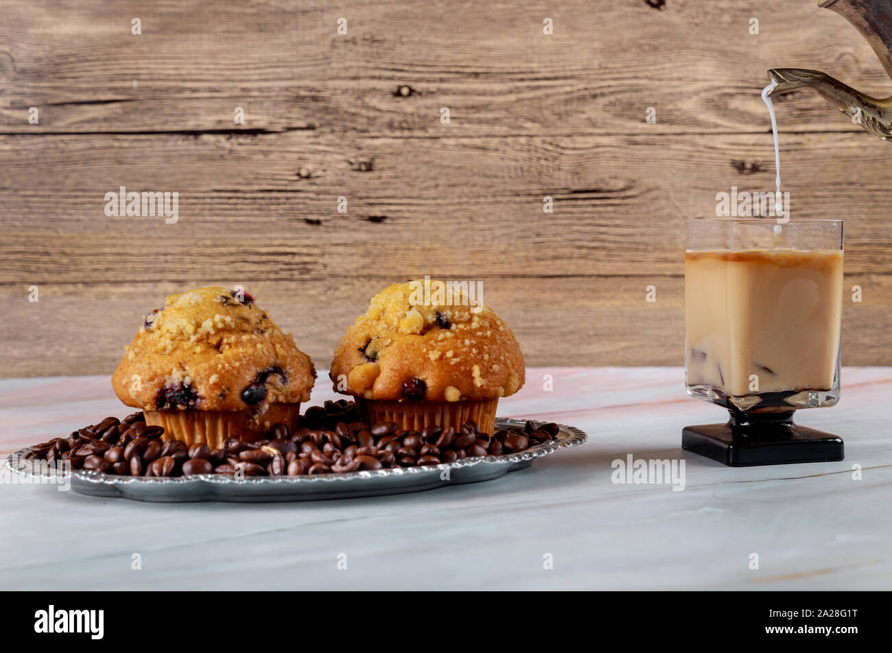 Infusion glacée café espresso dans un verre avec de la crème versé sur les grains de café cupcake chocolat savoureux Banque D'Images