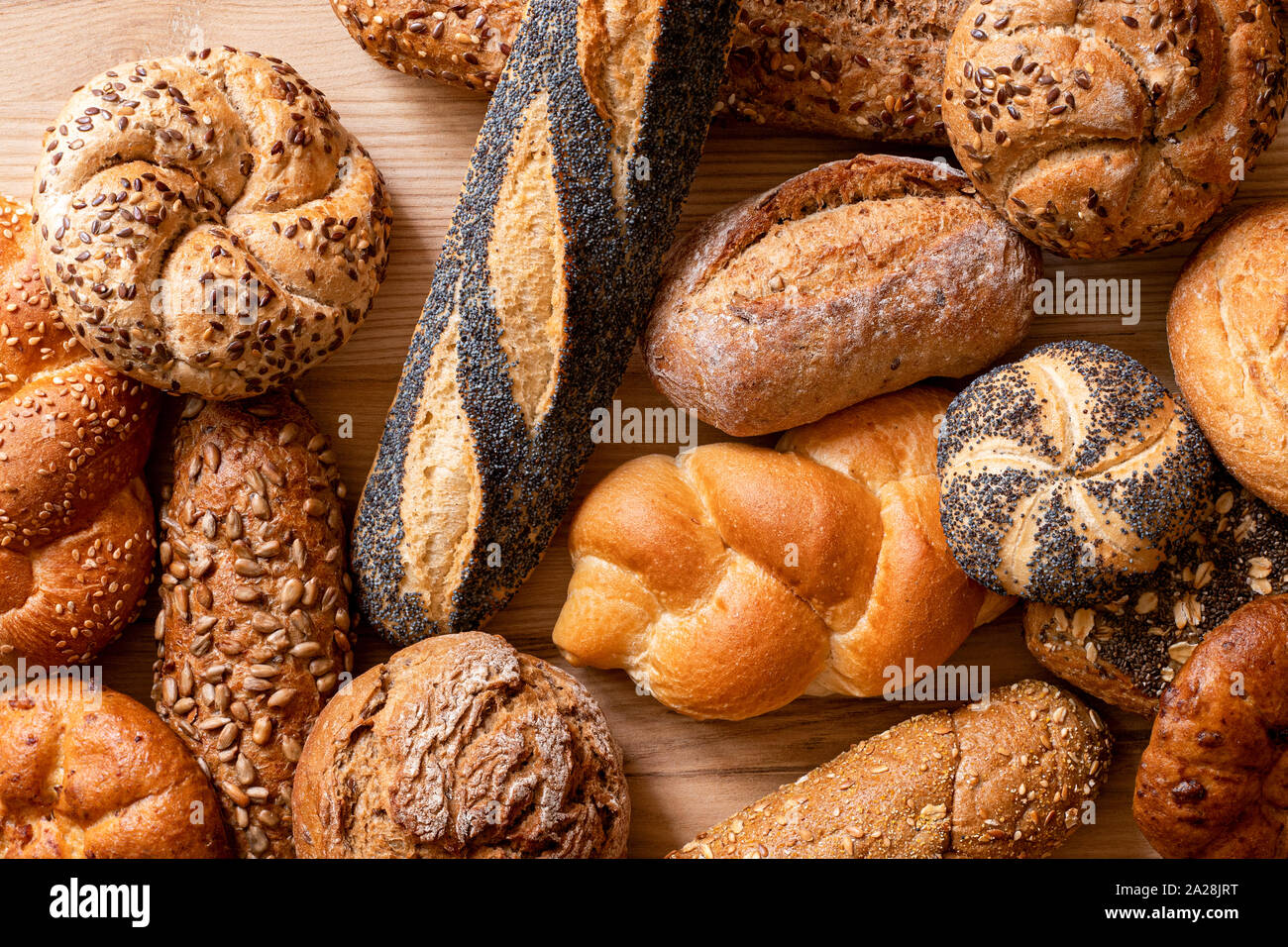 Arrière-plan de petits pains et baguettes mixtes sur bois clair. Vue d'en haut. Banque D'Images